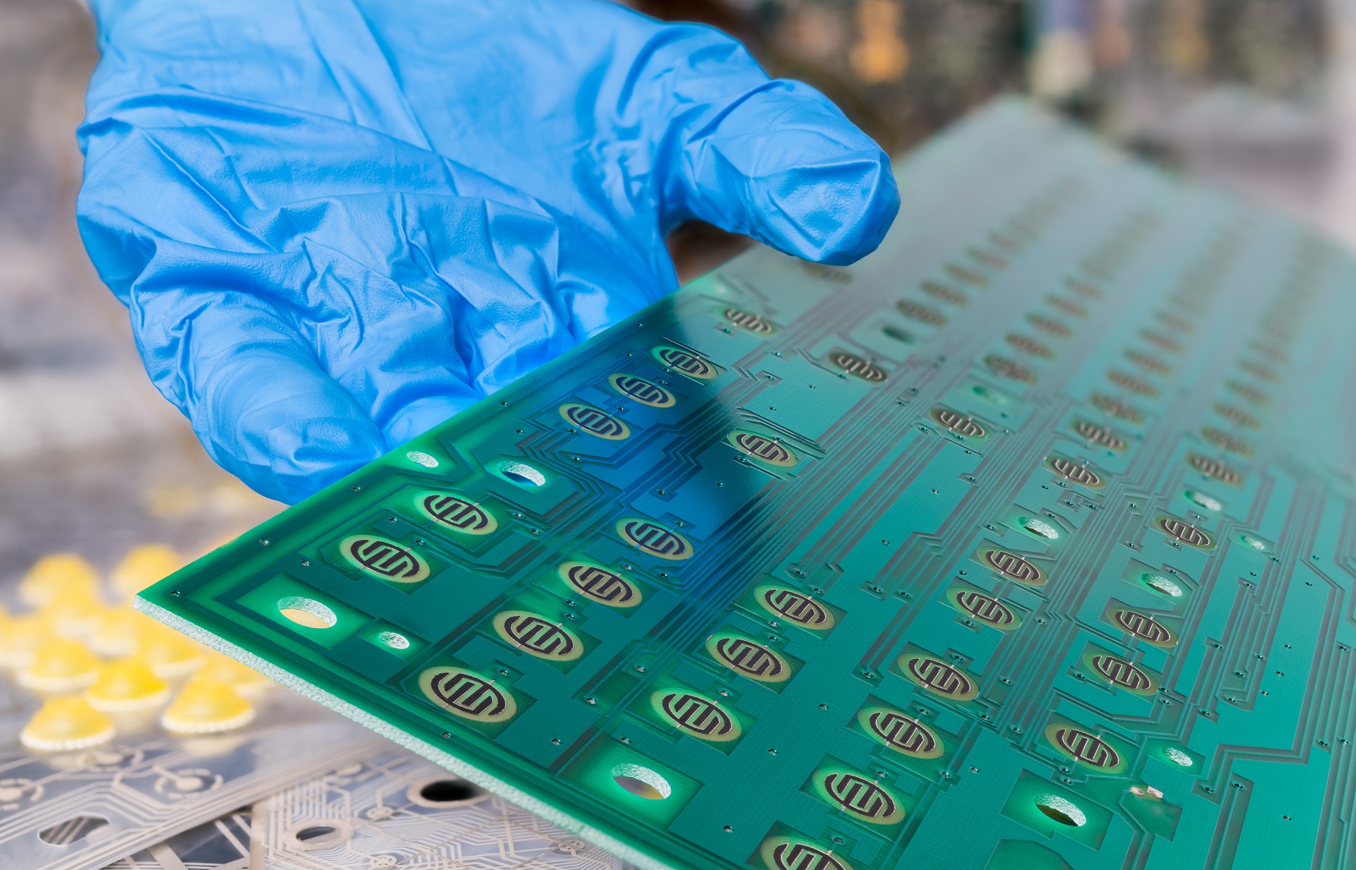 Printed circuit board of dismantled computer keyboard on human hand detail in blue glove